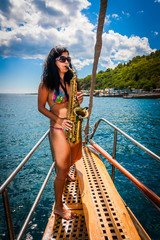 Girl playing the saxophone on a yacht in sea