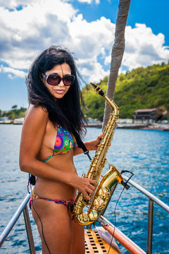 Girl playing the saxophone on a yacht in sea