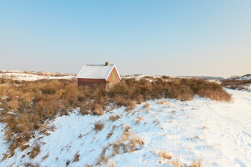 Lonely house in winter snow dune landscape with blue sky. The Ne
