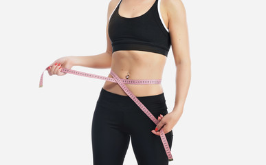 Young fitness woman measuring her waist