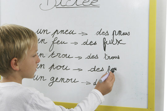 GARCON A L'ECOLE QUI ECRIT SUR UN TABLEAU