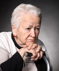 Portrait of old woman sitting with a cane