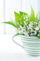 Lily of the valley flowers in a green striped cup
