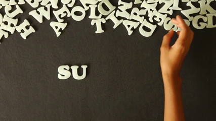 A person spelling Sunday with Plastic letters