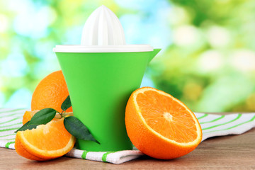 Citrus press and ripe oranges on brown wooden table