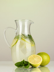 Lemonade in pitcher on green background