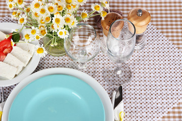 Table setting with chamomiles on checkered tablecloth