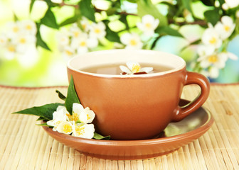 Cup of tea with jasmine, on bamboo mat, on bright background