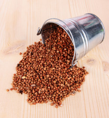 Overturned bucket with grains on wooden background