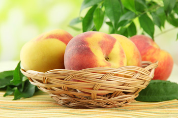 Ripe sweet peaches in basket on table, outdoors