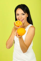 Girl with fresh juice and orange on green background