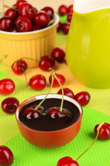 Ripe red cherry berries in bowl on wooden table close-up