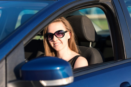 Beautiful businesswoman in sunglasses driving in the car