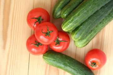 fresh tomatoes and cucumbers on a wooden table