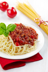 Spaghetti bolognese and green basil leaf on white plate