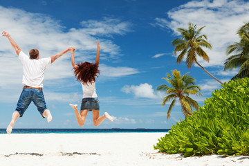 Happy couple jumping on the tropical beach