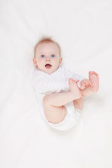 Cute baby with beautiful blue eyes lying in white bed