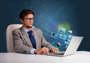 Young man sitting at desk and watching his photo gallery on lapt