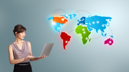 Young woman holding a laptop and presenting colorful world map