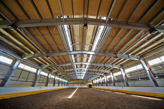 Indoor riding hall with sandy covering.