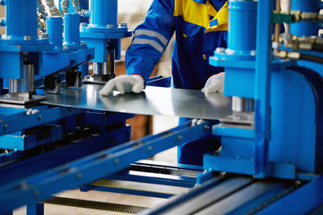 Sheet of metal and hands of worker who works on press - obrazy, fototapety, plakaty