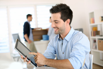 Smiling man in office working on digital tablet