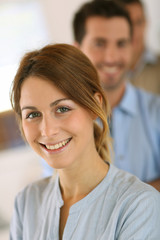 Cheerful young girl standing in front of business team