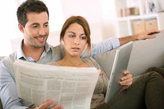 Couple reading news on both press and internet