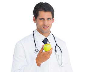 Fototapeta premium Doctor holding an apple and smiling at camera