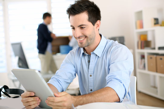 Smiling man in office working on digital tablet