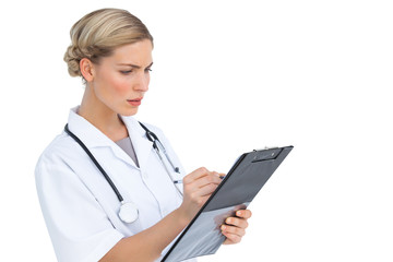 Serious nurse writing on clipboard