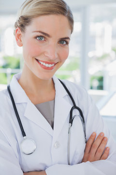 Smiling doctor standing with arms folded