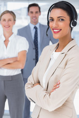 Fototapeta premium Smiling businesswoman with headset crossing her arms