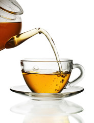 Tea pouring into glass cup isolated in white