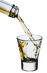 Whiskey being poured into a glass isolated on white