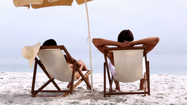 Couple relaxing under parasol