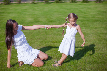 Young happy mother and her daughter having fun in the yard