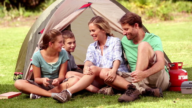 Family sitting in front of their tent spending time together