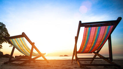 Loungers on the deserted coast sea at sunrise
