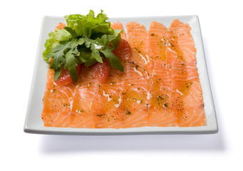 Salmon carpaccio served on white plate.