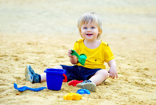 Adorable toddler playing with his toys in the sandpit