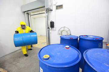 Worker in protective uniform, carrying blue barrel