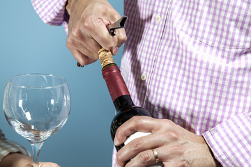 A man uncorking a bottle of red wine