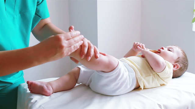 Physiotherapist massaging little baby boy foot