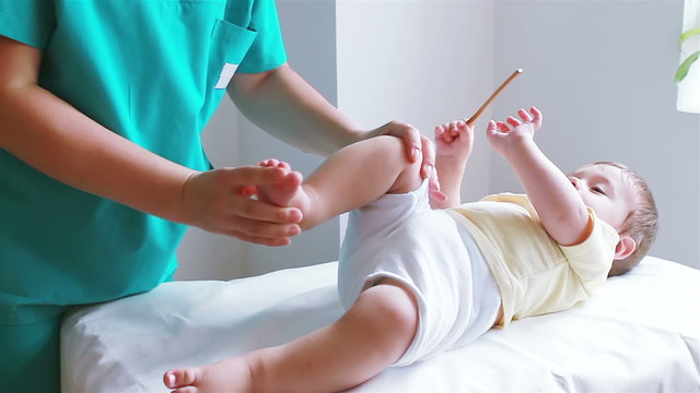Physiotherapist exercising with little baby boy foot