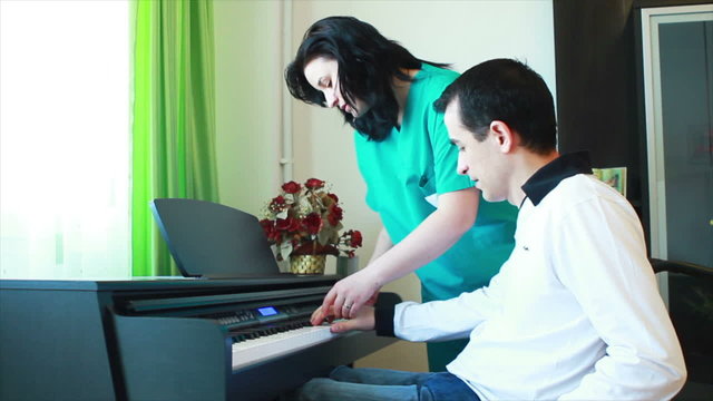 Therapy for young man in wheelchair using piano