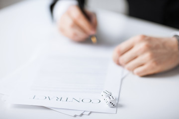 man hands with gambling dices signing contract