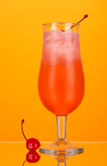 Cherry cocktail with ice on orange background