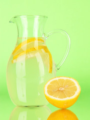 Lemonade in pitcher on green background