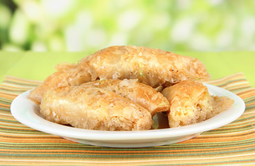Sweet baklava on plate on table on bright background